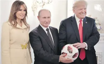  ?? KREMLIN POOL ?? U.S. First Lady Melania Trump, Russian President Vladimir Putin and U.S. President Donald Trump pose with a World Cup soccer ball from Russia after their summit in Helsinki, Finland, on Monday.