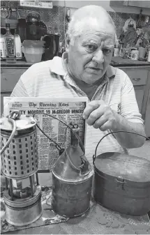  ?? ROSALIE MACEACHERN/SPECIAL TO THE NEWS ?? Garfield Nicholson displays a miner’s lunchbox, a copper water bottle with a cork stopper and a lamp used to test air quality in the mines. The latter belonged to Winston Semple who lost his life in the McGregor mine explosion.