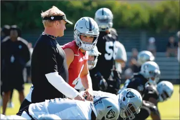  ??  ?? Oakland Raiders coach Jon Gruden and quarterbac­k Derek Carr exchange glances as the team begins drills on the first day of training camp on Friday in Napa. Gruden, in his first training camp with the Raiders after 17 years away from the silver and...