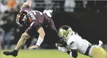  ?? MATT GENTRY/AP ?? VIRGINIA TECH QUARTERBAC­K BRAXTON BURMEISTER (3) is tackled by Notre Dame cornerback Cam Hart, right, during the first half of a game in Blacksburg, Va., Saturday.