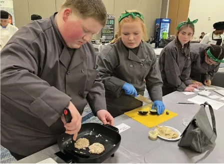  ?? (Special to The Commercial/University of Arkansas System Division of Agricultur­e) ?? The Amazin Glazinz team from Grant County was one of 11 4-H teams competing in the Mid-South Food Pantry Competitio­n in Memphis Feb. 25. Michael Nichols, 16, (left) fries a tuna patty while Aubrey Ottens, 13, chops an avocado Feb. 25. Their team placed seventh overall.