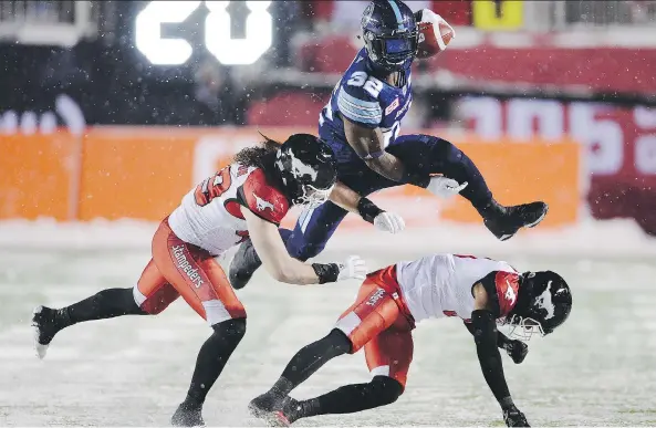  ?? RYAN REMIORZ/THE CANADIAN PRESS ?? Toronto Argonauts running back James Wilder Jr. leaps past Calgary Stampeders linebacker Alex Singleton, left, and defensive back Ciante Evans.