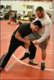  ?? MARK PODOLSKI — THE NEWS-HERALD ?? Mayfield’s Marco Tramontano, left, works with champion wrestler Kyle Snyder on Feb. 10 in Mentor.