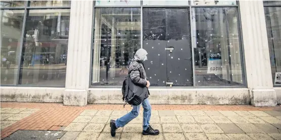  ?? KEVIN SCOTT ?? Crisis in store: A pedestrian walks past an empty shop front in a subdued Belfast city centre yesterday