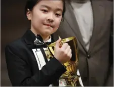  ?? PAUL CONNORS — BOSTON HERALD ?? Winship Elementary’s Tanoshi Inomata clutches the winning trophy at the conclusion of the BCYF Citywide Spelling Bee held at the Boston Public Library Saturday.