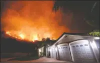  ?? The Associated Press ?? WILDFIRE: In this Aug. 9 photo a wildfire burns near homes in the Cleveland National Forest in Lake Elsinore, Calif. California homeowners may find themselves facing insurance issues even if they were not directly hit by this year’s blazes. The California Department of Insurance warned in January that the increasing number and severity of wildfires in the state were making it more difficult for homeowners to find and hold on to insurance. And now they say that recent massive fires may make the problem more acute.