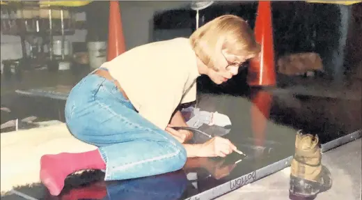  ?? ANNA CARROLL ?? Anna Carroll works on the floor of the historic Henry Ford Hangar at Lansing Municipal Airport as she etches images into granite slabs as the Lansing Veterans Memorial was taking shape in 1994. She later worked on Hammond’s police memorial.