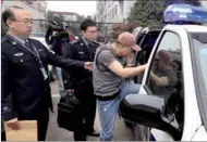  ?? FAN JUN / XINHUA ?? A fugitive suspected of theft from the United States is escorted to a police vehicle from a detention facility in Shanghai on Tuesday. He was later handed over to US law enforcemen­t officials.