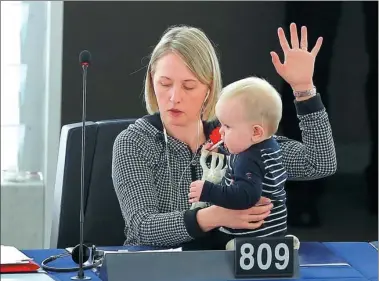  ?? VINCENT KESSLER / REUTERS ?? Swedish Member of the European Parliament Jytte Guteland holds her baby as she takes part in a voting session at the headquarte­rs in Strasbourg, France.