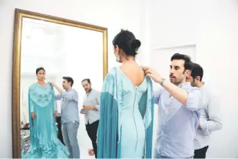  ?? ?? Fernandez (centre) helps with Jurado adjust a flamenco dress as Cuaresma tries it on, at his workshop in Seville.