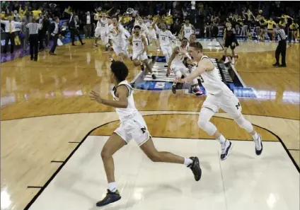  ??  ?? Michigan guard Jordan Poole (left) is chased by teammates after making a 3-point basket at the buzzer to win an NCAA men’s college basketball tournament second-round game against Houston on Saturday in Wichita, Kan. Michigan won 64-63. AP PHOTO/CHARLIE...