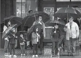  ?? Luis Sinco Los Angeles Times ?? THE ARZATE family takes cover from the rain in downtown L.A. during last week’s downpour. Southern California is set to see another storm system.