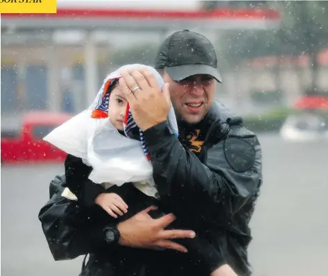  ?? GERALD HERBERT / THE ASSOCIATED PRESS ?? Sgt. Chad Watts of the Louisiana Department of Wildlife and Fisheries rescued Madelyn Nguyen, 2, and her family by boat in Houston on Monday.