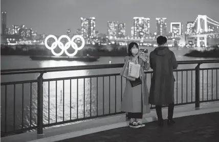  ??  ?? A woman wearing a face mask takes a selfie in front of the Olympic rings Wednesday in Tokyo. Concerns that the Tokyo Games may be postponed or cancelled are increasing as Japan confirms 862 cases of Coronaviru­s.