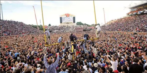  ?? AP/THE Daily Mississipp­ian/thomas GRANING ?? Thousands of Ole Miss students and supporters storm the field and attempt to bring down the goal posts Saturday after the No. 11 Rebels stunned No. 3 Alabama at Vaught-Hemingway Stadium in Oxford, Miss.