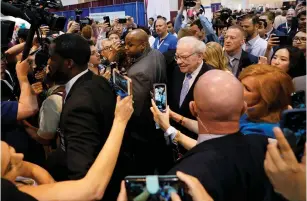  ??  ?? WARREN BUFFETT (center), the chairman and CEO of Berkshire Hathaway Inc., walks through the exhibit hall at the company’s annual meeting in Omaha, Nebraska, on Saturday.