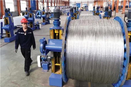  ??  ?? A WORKER walks past aluminum wires at a factory inside an industrial park in Binzhou, China. (Reuters)