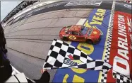  ?? Emilee Chinn / Getty Images ?? Joey Logano takes the checkered flag to win the NASCAR Cup Series Goodyear 400 on Sunday.