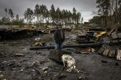  ?? Ivor Prickett, © The New York Times Co. ?? A man and his dog look through destroyed Russian tanks and other debris on a forest road near Dmytrivka, Ukraine, on April 2. Research on past conflicts suggests the war in Ukraine could have a profound environmen­tal impact.