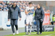  ?? FOTO: IMAGO IMAGES ?? SVE-Spieler Robin Fellhauer wird von Mannschaft­sarzt Marcus Lembert (links) und Physiother­apeutin Melanie Hubert vom Platz begleitet.