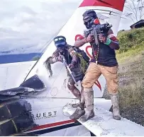  ?? SEBBY SEMBOM FOR CEPOS ?? DIBURU APARAT: Dua orang yang diduga anggota KKB naik ke puing pesawat sambil menunjukka­n senjatanya.