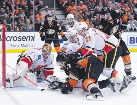  ?? HARRY HOW ?? Flames’ goaltender Brian Elliott shuts the door on Ducks’ Rickard Rakell (67) as teammates Mikael Backlund (11) and Michael Stone (26) battle for the loose puck in Game 1 of their Western Conference quarter-final series on Thursday at the Honda Center in Anaheim. Ducks won it, 3-2.