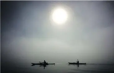  ?? — THE CANADIAN PRESS ?? Kayaking in North Vancouver’s Deep Cove are silhouette­d by the sun as they paddle though thick fog in Deep Cove in North Vancouver.