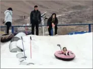  ?? KUNGA LESANG / FOR CHINA DAILY ?? People have fun at a snow-sliding attraction at an amusement park in Lhasa, capital of the Tibet autonomous region, on Feb 20. A small ski slope and a snow-bike area were also set up to help visitors celebrate the 2022 Beijing Winter Olympic Games.