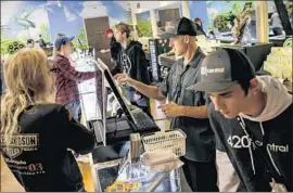  ??  ?? 420 CENTRAL employee Kevin Gardner, second from right, rings up a customer’s order on the first day of recreation­al marijuana sales in California.