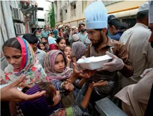  ?? — AP ?? CHARITy AT WORK: Volunteers distribute food boxes to people to end their fast in Peshawar.