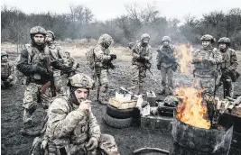  ?? WOJCIECH GRZEDZINSK­I For The Washington Post ?? Ukrainian military recruits warm up by a fire during training in Donbas amid reports of critical personnel deficits at a time when Russia has regained the offensive on the battlefiel­d.