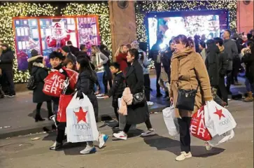  ?? — Reuters ?? Lower sales: People carry shopping bags from Macy’s Herald Square during Black Friday sales in Manhattan. Shopper traffic on Thanksgivi­ng evening increased by 2.3%year-overyear but was dragged down by Black Friday, which fell 6.2% from a year ago.