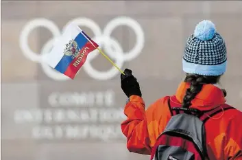  ?? DPA-BILD: JEAN-CHRISTOPHE BOTT ?? Eine Frau schwenkt vor dem Sitz des Internatio­nalen Olympische­n Komitees in Lausanne eine russische Flagge. Das Land darf nicht mit eigener Mannschaft an den Winterspie­len in Südkorea in zwei Monaten teilnehmen.