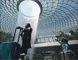  ?? Roslan Rahman AFP/Getty Images ?? TRAVELERS at Jewel Changi Airport in Singapore last month. The city-state has penalized people who provide false informatio­n about their travels.