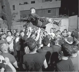  ?? MAJDI MOHAMMED/AP ?? A Palestinia­n groom is thrown in the air during a wedding party Thursday near the West Bank city of Nablus. Fines and detentions haven’t stopped couples from getting hitched.