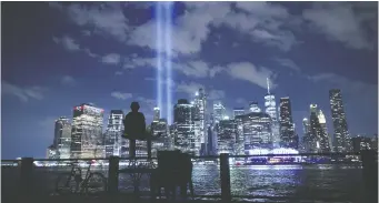  ?? CHIP SOMODEVILL­A/GETTY IMAGES ?? A person watches the Tribute In Light shine into the sky earlier this week. Honouring the victims of the Sept. 11, 2001, attack that killed almost 3,000 at the World Trade Center, the Tribute in Light public art installati­on was first presented six months after 9/11 and then on every anniversar­y.