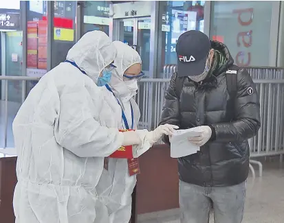  ??  ?? Lu Juan (center), a teacher from the Xiehe Education Group, and another volunteer instruct a foreigner on filling in the health statement form at Hongqiao Railway Station. — Ti Gong