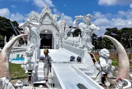  ?? — AP ?? A worker puts finishing touches on a community puja pandal modelled on the White Temple of Thailand ahead of the Durga Puja festival in Kolkata on Friday.