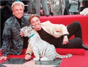  ??  ?? The Associated Press
Illusionis­ts Siegfried Fischbache­r, left and Roy Uwe Ludwig Horn pose for photograph­ers with a white tiger cub in Los Angeles, Calif.