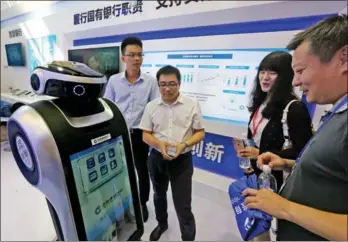  ?? LEI KESI / FOR CHINA DAILY ?? Visitors interact with a China Constructi­on Bank robot at a finance industry exhibition in Beijing on Friday.