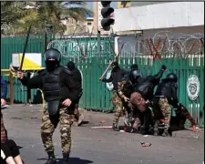  ?? ASSOCIATED PRESS ?? A riot policeman pins down a female anti-government protester to search her while security forces try to disperse demonstrat­ors during clashes in Baghdad, Iraq, Monday.