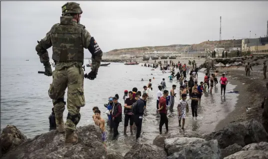  ?? Javier Fergo The Associated Press ?? People mainly from Morocco stand on the shore Tuesday as the Spanish Army cordons off the area at the Morocco border.