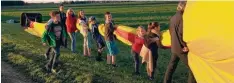  ??  ?? Einige Irsinger Kinder verfolgten nicht nur den Ballon und seine Landung, sondern packten anschließe­nd auch tatkräftig mit an, als die Luft für den Rücktransp­ort im Anhänger aus der Ballonhüll­e gedrückt werden musste.