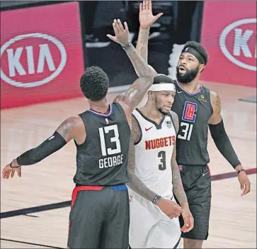  ?? Douglas P. DeFelice Getty Images ?? PAUL GEORGE and Marcus Morris Sr. exchange a high-five over Denver’s Torrey Craig during the second quarter of the Clippers’ victory. The Nuggets were coming off a seven-game series that ended Tuesday.