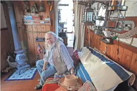  ?? PHOTOS BY MICHAEL SEARS / MILWAUKEE JOURNAL SENTINEL ?? Mark Gubin sits on the sofa in what he has made
into the living room on the tug. A stove at left is for when it's cold out.