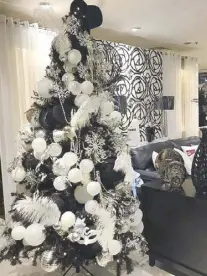  ??  ?? For a Cosmopolit­an Christmas, this black tree reflects the glamour and sophistica­tion of city living. Black velvet top hats, white and black feathers, masks and balls add an opulent feel. Available at Our Home.