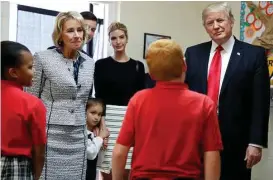  ?? Alex Brandon / Associated Press ?? President Donald Trump joins Education Secretary Betsy DeVos and his daughter, Ivanka, in chatting with students on Friday during a tour of St. Andrew Catholic School in Orlando, Fla.