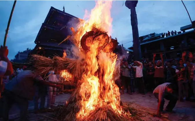  ??  ?? Nepali devotees watch as a straw effigy of Ghanta Karna burns during celebratio­ns of the Hindu festival of “Gathemanga­l”, also known as Ghanta Karna, in Bhaktapur on the outskirts of Kathmandu on July 30, 2019. The Nepali festival, which celebrates the defeat of the mythical demon Ghanta Karna (“bell-ears”), is celebrated by performing the legendary drama in the streets. — AFP