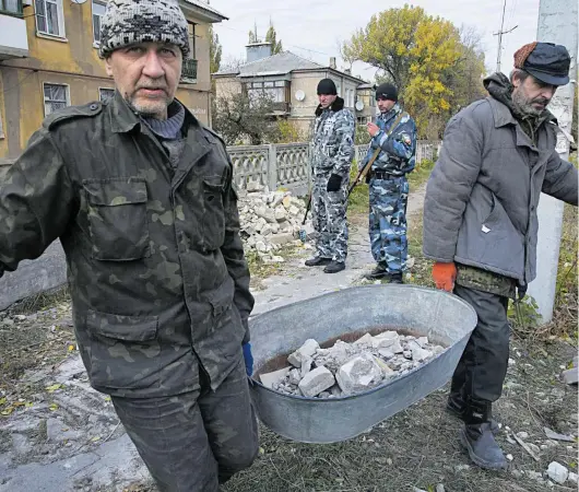  ?? FOT. DMITRY LOVETSKY/AP ?? • Ukraińscy jeńcy wojenni usuwają gruzy z uszkodzone­go budynku w Iłłowajsku na wschodzie Ukrainy