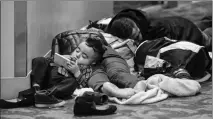  ?? JOHN SPINK/ATLANTA JOURNAL-CONSTITUTI­ON VIA AP ?? KENNETH REYES, 2, WATCHES PHONE CARTOONS as his parents, Lucas and Areli, and sister, Yosselyn, 11, sleep on the second floor of the atrium overnight into Monday morning at Hartsfield-Jackson Internatio­nal in Atlanta.